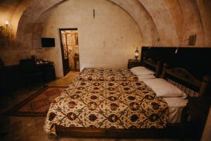 a bedroom with a bed with a comforter on it at Artium Cave Hotel in Mustafapaşa