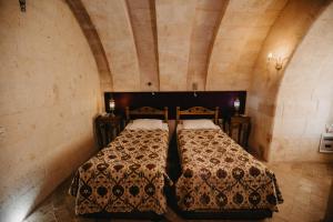 1 dormitorio con 2 camas y 2 mesitas de noche en Artium Cave Hotel, en Mustafapaşa