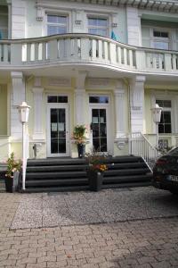 une maison blanche avec des escaliers et un balcon. dans l'établissement Hotel Rosengarten, à Bad Salzuflen