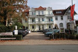 une grande maison blanche avec des voitures garées devant elle dans l'établissement Hotel Rosengarten, à Bad Salzuflen