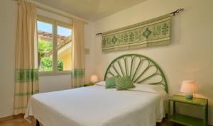 - une chambre avec un lit blanc et une fenêtre dans l'établissement Residence Le Bouganville, à Villasimius