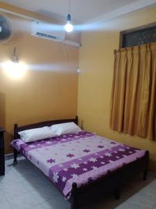 a bedroom with a bed with purple sheets and a fan at Relaxing apartment l Revenla garden l in Matara