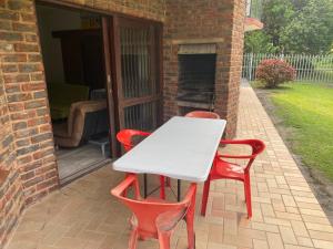 a white table and four red chairs on a patio at See Uitsig 2 in Uvongo Beach +4 photos