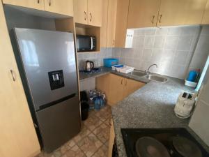 a small kitchen with a stainless steel refrigerator at See Uitsig 2 in Uvongo Beach