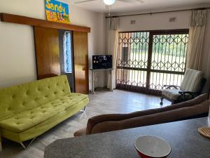 a living room with a yellow couch and a tv at See Uitsig 2 in Uvongo Beach