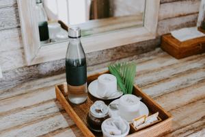 - une bouteille de vin assise sur un plateau avec des théières dans l'établissement Lanussa Hill Villa, à Nusa Lembongan