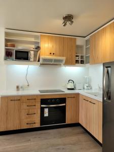 una cocina con armarios de madera y un aparato negro en Playa Paraíso Resort, en Concón
