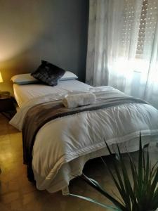 um quarto com uma cama com lençóis brancos e uma planta em El Refugio Bed & Breakfast em Villarrobledo