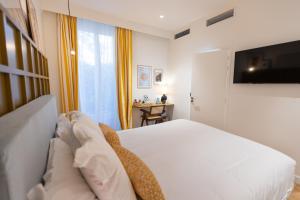 um quarto com uma cama branca e uma televisão em Maison Durante em Nice