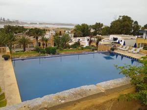 a large swimming pool with blue water at sultana duplex 3 pour les familles in Oualidia