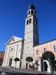 Una iglesia con una torre con un reloj. en Villesse Appartamenti, 