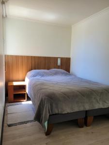 1 dormitorio con 1 cama grande y pared de madera en Playa Paraíso Resort, en Concón