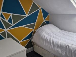 a small bedroom with a bed and a geometric wall at Three Bedroomed House in Morecambe in Morecambe
