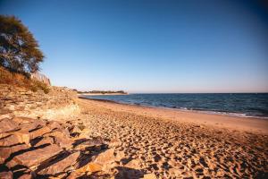 a sandy beach with rocks and the ocean at Le Phare in Les Portes