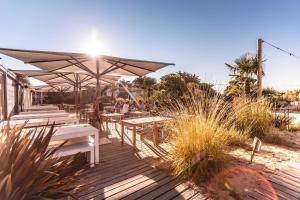 ein Restaurant mit Tischen und Sonnenschirmen auf einer Terrasse in der Unterkunft Le Phare in Les Portes