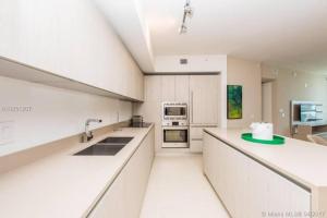 a large white kitchen with white counters and appliances at Modern Beachfront Condo with Stunning Ocean View in Hollywood