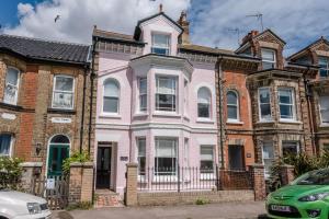 una casa rosa en una fila de casas de ladrillo en The Pink House in Southwold - Air Manage Suffolk, en Southwold