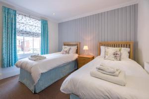 two beds in a bedroom with a window at The Pink House in Southwold - Air Manage Suffolk in Southwold