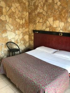a bedroom with a bed and a chair and a stone wall at American Motel in Cisterna di Latina