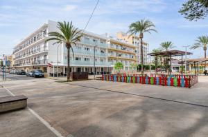 an empty street with a building and palm trees at Hostal Gami Adults Only in Cala Ratjada