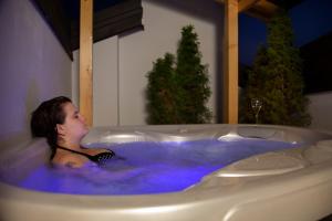 une femme assise dans une baignoire avec eau bleue dans l'établissement Hotel Romanda, à Levico Terme