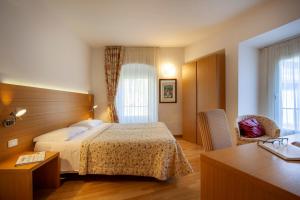 una camera d'albergo con letto e scrivania di Hotel Romanda a Levico Terme
