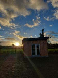 a small building with a sunset in the background at Stoneyford Luxurious Cabins in Stonyford