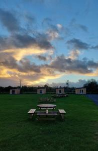 a picnic table in a field with a cloudy sky at Stoneyford Luxurious Cabins in Stonyford