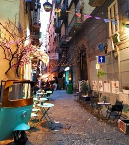 una strada con tavoli e sedie e uno scooter parcheggiato in un vicolo di Il Dubbio ai Quartieri Spagnoli a Napoli