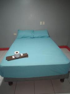 Una cama azul con una bandeja con una vela. en HOTEL LAS CAPERUZAS, en Guayaquil