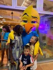 a group of children standing in front of a large mascot at Camping Paradis Le Pressoir in Petit-Palais-et-Cornemps