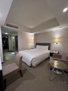 a hotel room with a large white bed and chairs at Forward Suites Ⅰ in Taipei