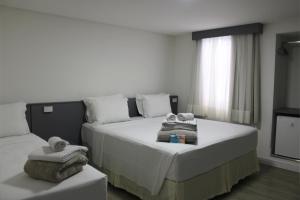 1 dormitorio con 1 cama con toallas en Sagres Praia Hotel, en Balneário Camboriú