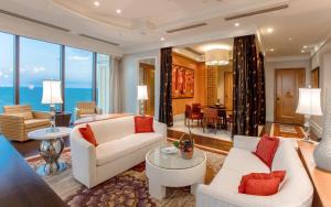 a living room with white furniture and large windows at InterContinental Grand Ho Tram in Ho Tram