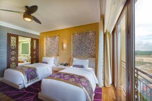 two beds in a hotel room with a balcony at InterContinental Grand Ho Tram in Ho Tram