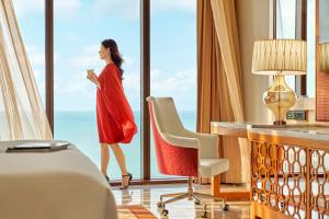 a woman in a red dress standing in front of a window at InterContinental Grand Ho Tram in Ho Tram