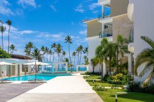 a resort with a swimming pool and palm trees at Family Getaway Apartment - Right On The Beach in Punta Cana
