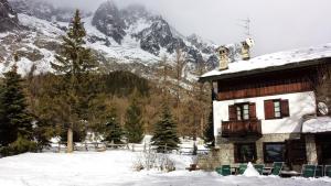 a house in the snow with a mountain in the background at Hotel Locanda Belvedere in Courmayeur