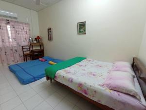 a bedroom with two beds and a table in it at Heawood Homestay Sungai Siput in Sungai Siput