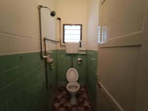 a bathroom with a toilet with a window and green tiles at Heawood Homestay Sungai Siput in Sungai Siput