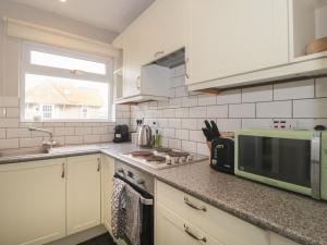 una cucina con forno a microonde e piano di lavoro di 24 Heron Court a Bridport