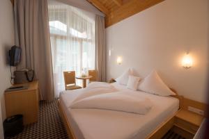 a hotel room with a white bed and a window at Hotel Tristkogel in Saalbach Hinterglemm