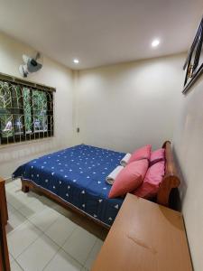 a bedroom with a bed with blue sheets and pink pillows at Happy Valley Pattaya in Jomtien Beach