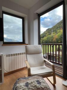 Una silla blanca sentada en una habitación con balcón en Apartament La Gisca, en Valencia de Aneu