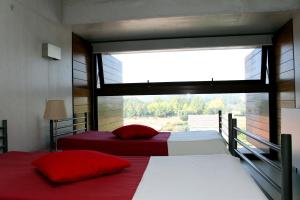 two beds in a room with a large window at HI Ponte de Lima - Pousada de Juventude in Ponte de Lima