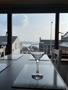 a wine glass sitting on a table in front of a window at Kennys apartment in Milford Haven