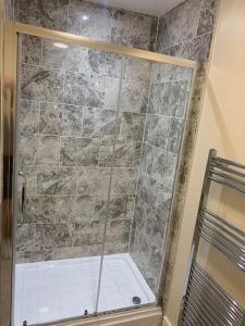 a shower with a glass door in a bathroom at Kennys apartment in Milford Haven