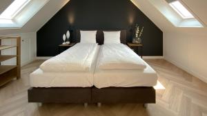 1 dormitorio con 1 cama grande con sábanas y almohadas blancas en Waterrijk Oesterdam Resort Villas, en Tholen