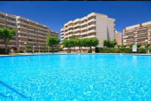 een groot blauw zwembad met gebouwen op de achtergrond bij Apartamento en Salou con 3 piscinas junto a Port Aventura in Salou