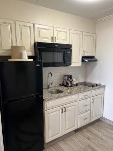 a kitchen with a black refrigerator and white cabinets at Dunes Suites Oceanfront in Ocean City